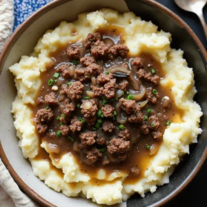 A hearty plate of ground beef and mashed potatoes, topped with rich brown gravy and garnished with fresh parsley.